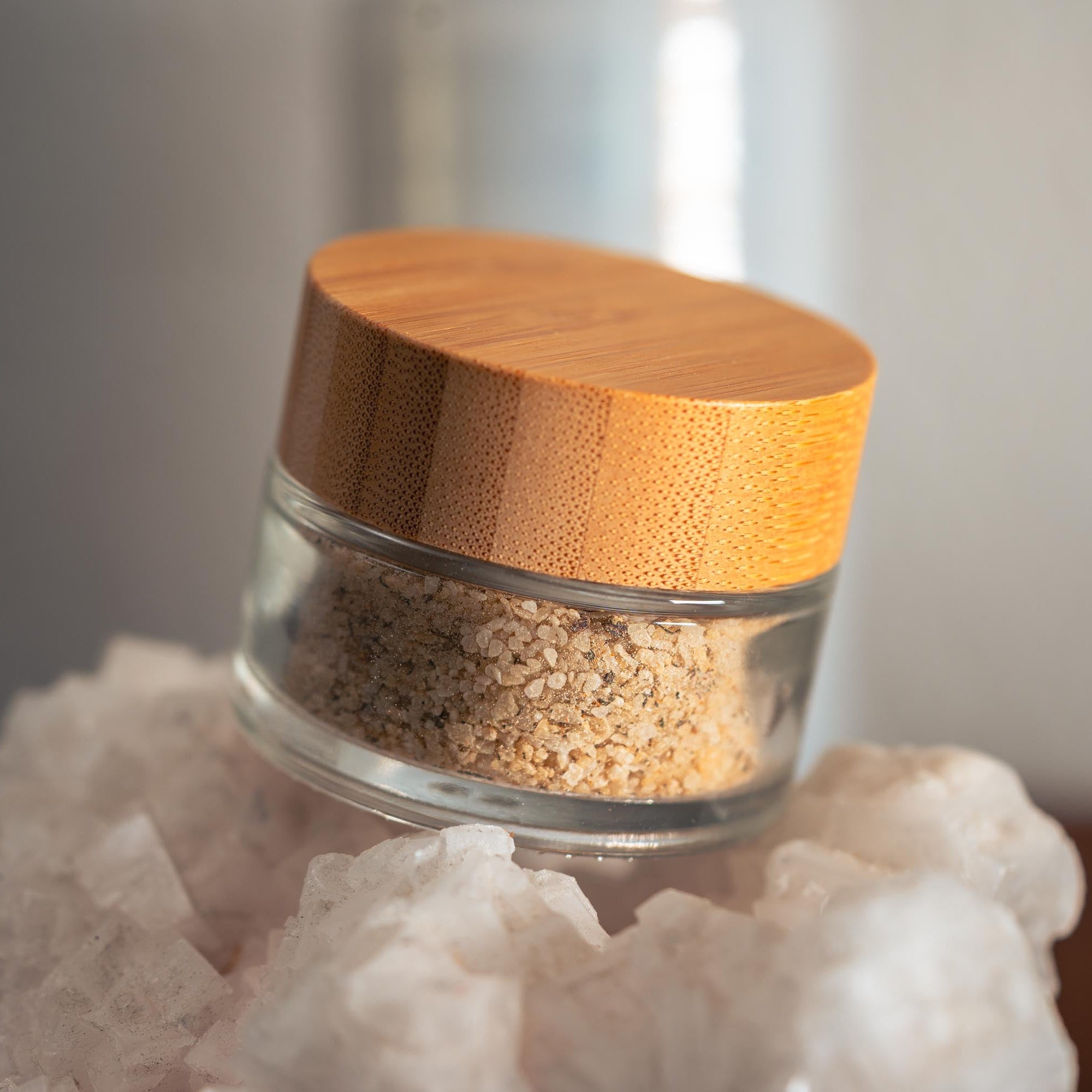 Glass jar with wooden lid on a white rock against a neutral background